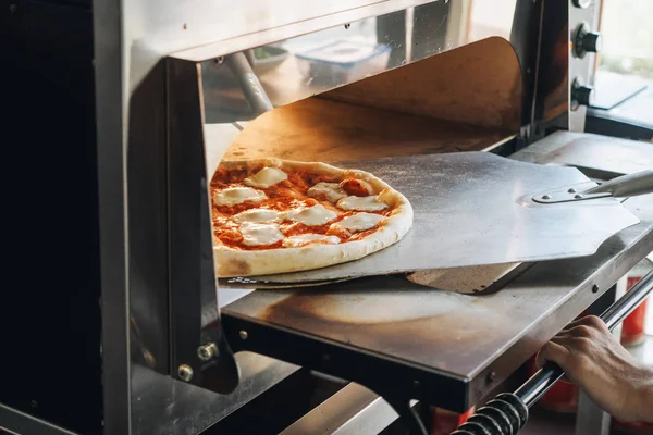 Кулинария в современной печи для пиццы на кухне кафе — стоковое фото