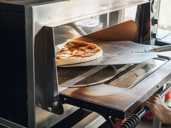 Кулинария в современной печи для пиццы на кухне кафе — стоковое фото