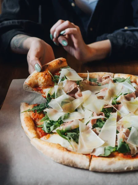 Pizza with parma ham, cheese, arugula, sauce in rustic cafe table