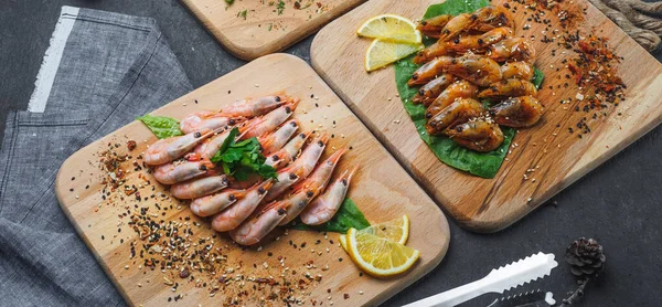 Raw and fried shrimps with lemon on wooden board