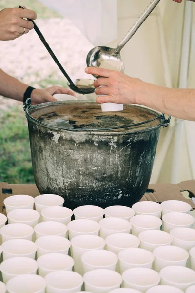 Un bénévole verse des boissons aux pauvres dans un centre caritatif — Photo