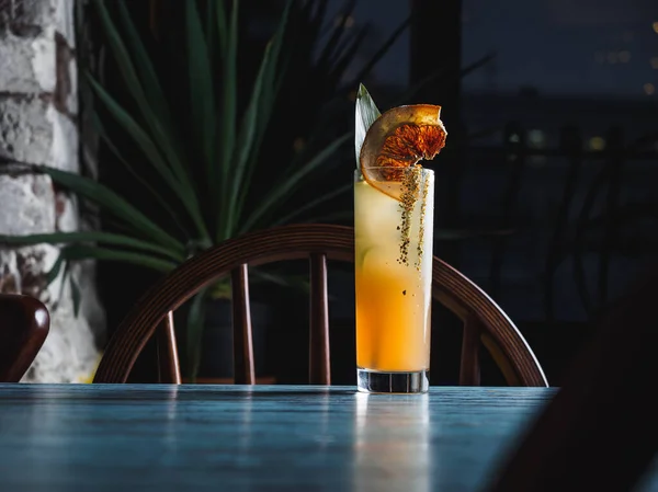 Oranžový tropický koktejl v hogballovém skle na modrém stole — Stock fotografie