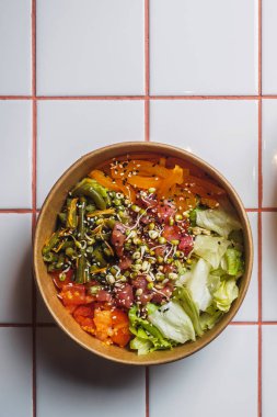 Beyaz fayans masasında ton balığı ve sebzeli dürt.