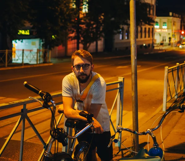 Man with cruiser bicycle in night city street.