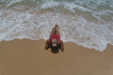 Kırmızı mayo kuma üzerinde seksi modeli yatıyor