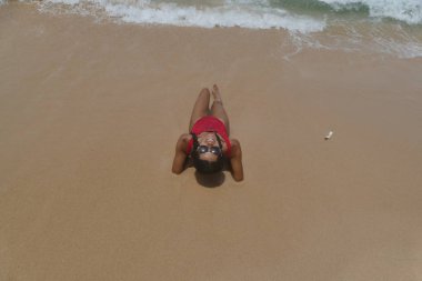 Kırmızı mayo kuma üzerinde seksi modeli yatıyor