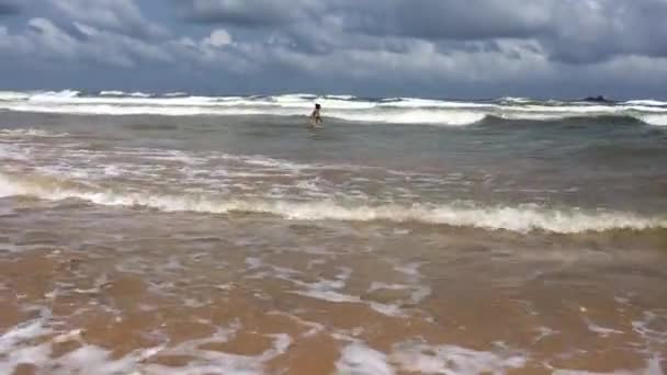 年轻美丽的女子跳跃和在海洋里的波浪上玩 — 图库视频影像