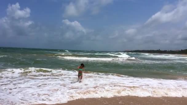 तरुण आणि सुंदर स्त्री उडी आणि महासागरात लाटांवर खेळत — स्टॉक व्हिडिओ