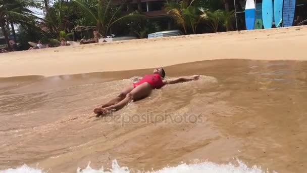 Una chica sexy en traje de baño rojo sale corriendo del océano — Vídeo de stock