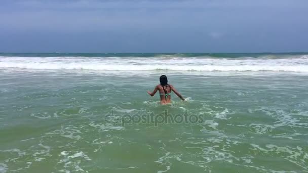 Молодая и красивая женщина прыгает и играет на волнах океана — стоковое видео