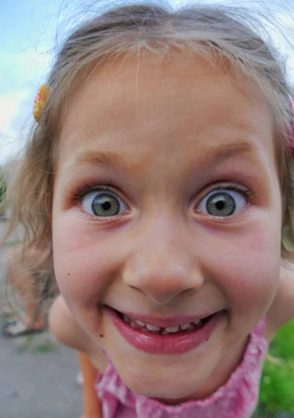 Yakın çekim kamera lensi ilgiyle benzeyen bir yaramaz komik kız portresi