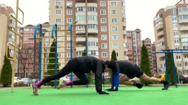 Güzel genç çift dışarıda çalışıyor plang, squat, hamleler, şınav çekiyorlar
