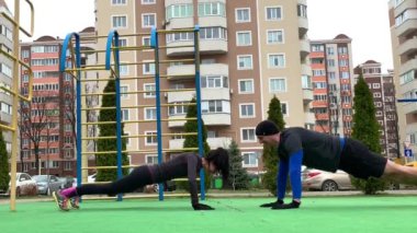 Güzel genç çift dışarıda çalışıyor plang, squat, hamleler, şınav çekiyorlar