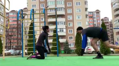 Güzel genç çift dışarıda çalışıyor plang, squat, hamleler, şınav çekiyorlar