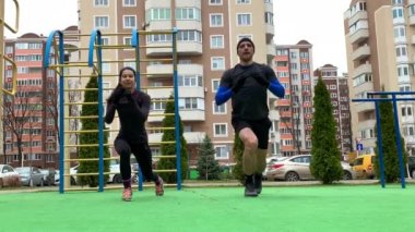 Güzel genç çift dışarıda çalışıyor plang, squat, hamleler, şınav çekiyorlar