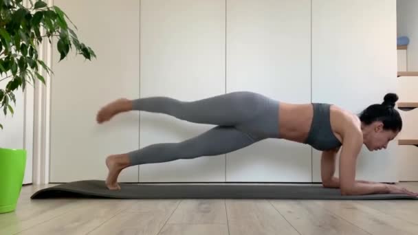 スポーツウェアの若いフィットネス女性は自宅やスタジオでプランク運動を行う 隔離中の動的板 胃の筋肉を動作させる演習 — ストック動画