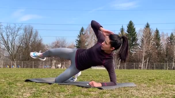 年轻健康女性穿着运动服在草坪上做冲浪板运动 体育馆的锻炼 检疫过程中的动力板 做运动锻炼胃肌肉 — 图库视频影像