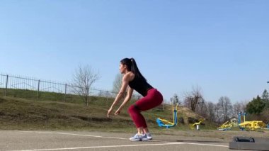Kadın spor antrenmanı ve sabah dışarıda çalışma. Güçlü ve sportif kadın hamleler yapıyor, çömeliyor, burpee yapıyor.