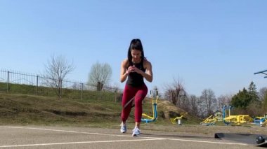 Kadın spor antrenmanı ve sabah dışarıda çalışma. Güçlü ve sportif kadın hamleler yapıyor, çömeliyor, burpee yapıyor.