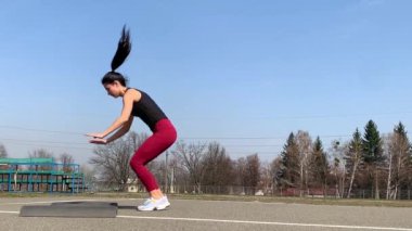 Kadın spor antrenmanı ve sabah dışarıda çalışma. Güçlü ve sportif kadın hamleler yapıyor, çömeliyor, burpee yapıyor.