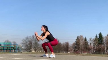 Kadın spor antrenmanı ve sabah dışarıda çalışma. Güçlü ve sportif kadın hamleler yapıyor, çömeliyor, burpee yapıyor.