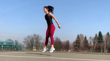 Kadın spor antrenmanı ve sabah dışarıda çalışma. Güçlü ve sportif kadın hamleler yapıyor, çömeliyor, burpee yapıyor.