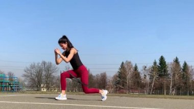 Kadın spor antrenmanı ve sabah dışarıda çalışma. Güçlü ve sportif kadın hamleler yapıyor, çömeliyor, burpee yapıyor.