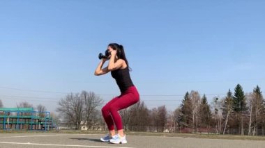 Kadın spor antrenmanı ve sabah dışarıda çalışma. Güçlü ve sportif kadın hamleler yapıyor, çömeliyor, burpee yapıyor.