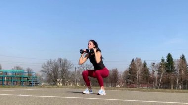 Kadın spor antrenmanı ve sabah dışarıda çalışma. Güçlü ve sportif kadın hamleler yapıyor, çömeliyor, burpee yapıyor.