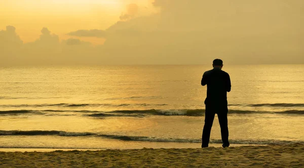 Силуэты людей на пляже на восходе солнца — стоковое фото