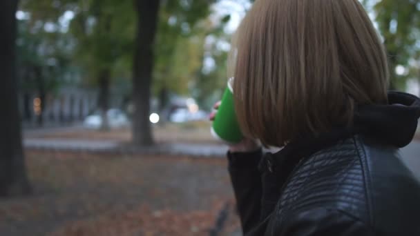 Genç kadın içecekler kahve akşam sokakta — Stok video