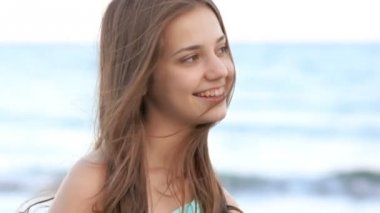 Uzun saçlı genç kız sahilde, gülümseyen, Rüzgar hava güler