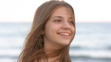 Uzun saçlı genç kız sahilde, gülümseyen, Rüzgar hava güler