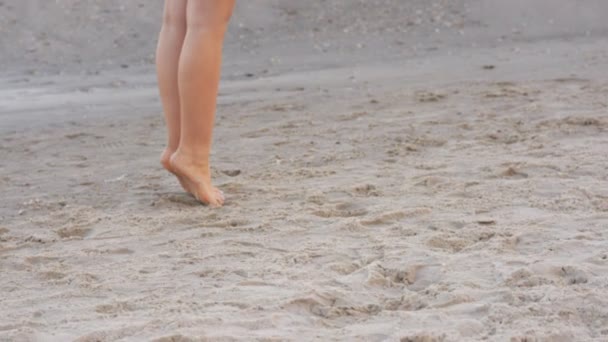 Дівчина босоніж, що зупиняється на морському пляжі, панорама від ніг до голови — стокове відео