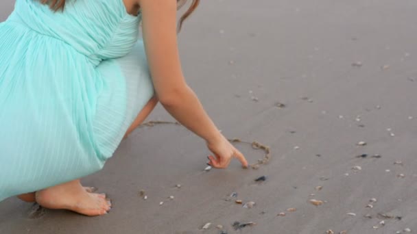 Kvinna ritning hjärtat på stranden sand med havet skum — Stockvideo