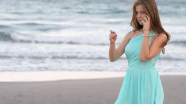 Esmer kadın denizin kenarında cep telefonunuzla günbatımında söz — Stok video