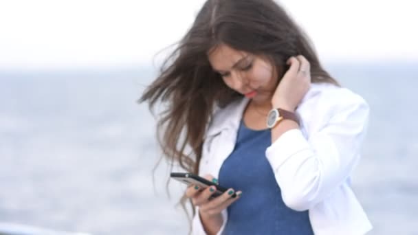 Mujer caminando cerca del mar con smartphone, esperando a alguien — Vídeo de stock
