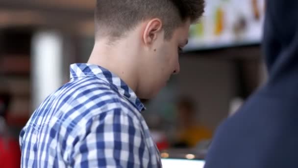 Мужчина покупает фаст-фуд в ресторане быстрого питания — стоковое видео
