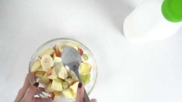 Hermosa chica manos mezclando ensalada de frutas en un tazón de vidrio — Vídeos de Stock