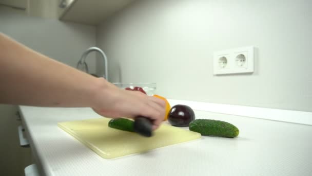 Приготування їжі - розрізання огірків на білій кухні в салат — стокове відео