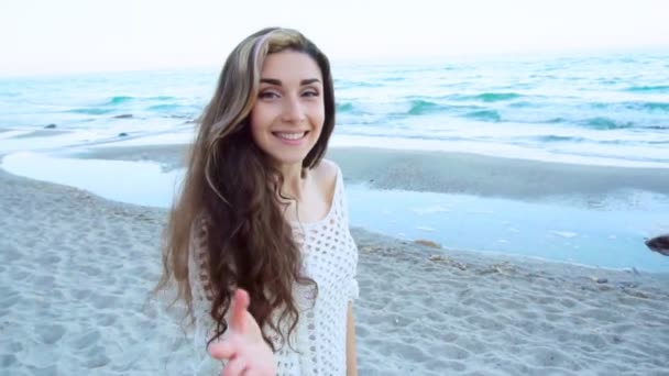 Женщина просит следовать за ней к песчаному пляжу у синего моря — стоковое видео