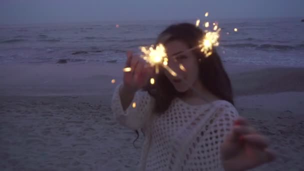 Vrouw plezier met wonderkaarsen in de buurt van de zee op de avond — Stockvideo