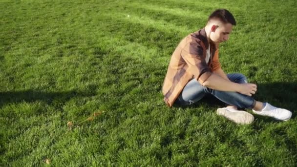 Man sitting at the grass using smartphone when his girlfriend came — Stock Video