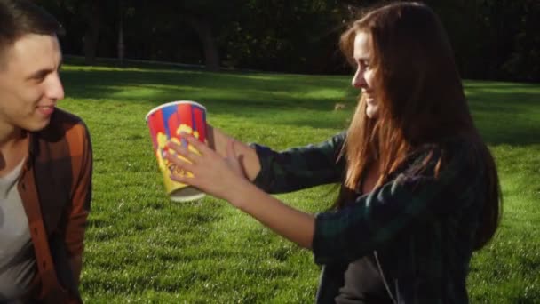 Woman presents popcorn to her boyfriend and they start eating — Stock Video