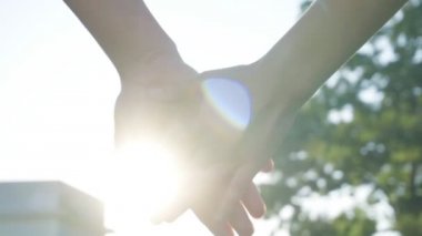 Ağır çekim güneşli bir günde, el ele tutuşarak Çift