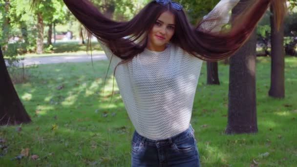 Mujer en el parque juega con su pelo cayendo de las manos — Vídeos de Stock