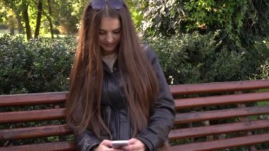 Uzun saçlı güzel kadın hücre smartphone açık havada parkta kullanır
