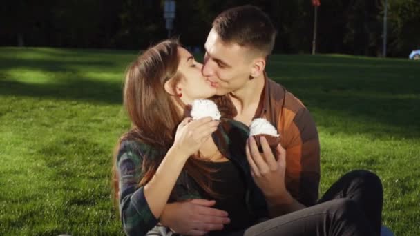 Paar auf dem Gras isst Kuchen und hat Spaß — Stockvideo