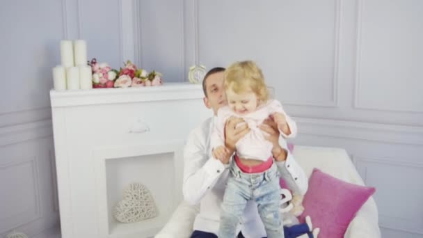 Father plays with his baby girl near the fireplace — Stock video