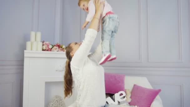 Mother plays with her baby girl embracing and kissing — Stock video